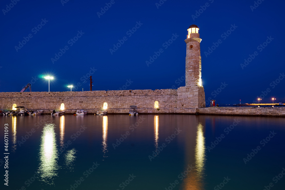 An historic stone wall and a lighthouse in the port of Rethymno on the island of Crete