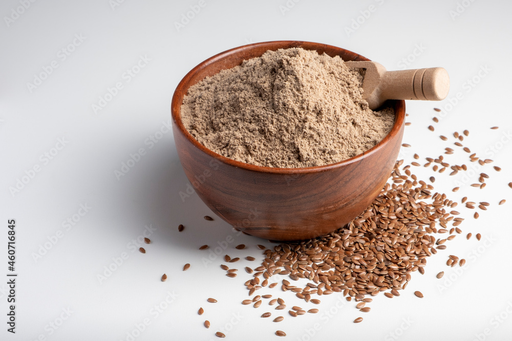 Raw flax seeds flour in a wooden bowl with on white background. Raw flax seeds flour in a wooden bowl with on white background.