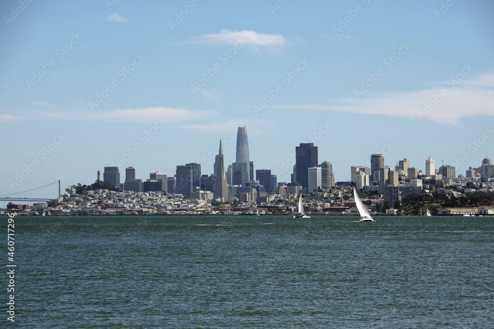 San Francisco skyline with sailboats in front under blue sky seen across the water in early August of 2021