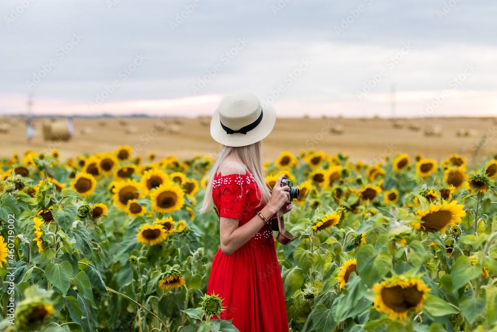 Woman holding camera for photographer on field of sunflowers. She is rest day summer travel holidayst