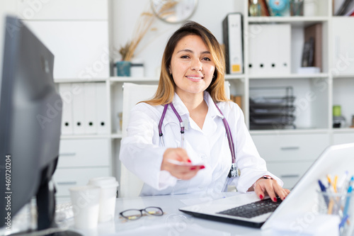 Mexican woman doctor in uniform is giving recipe to client in clinic