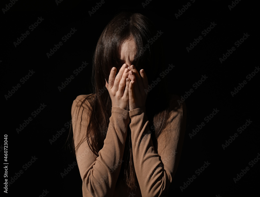 Scared young woman on dark background. Concept of harassment Scared young woman on dark background. Concept of harassment