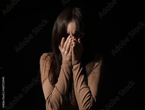 Scared young woman on dark ...
