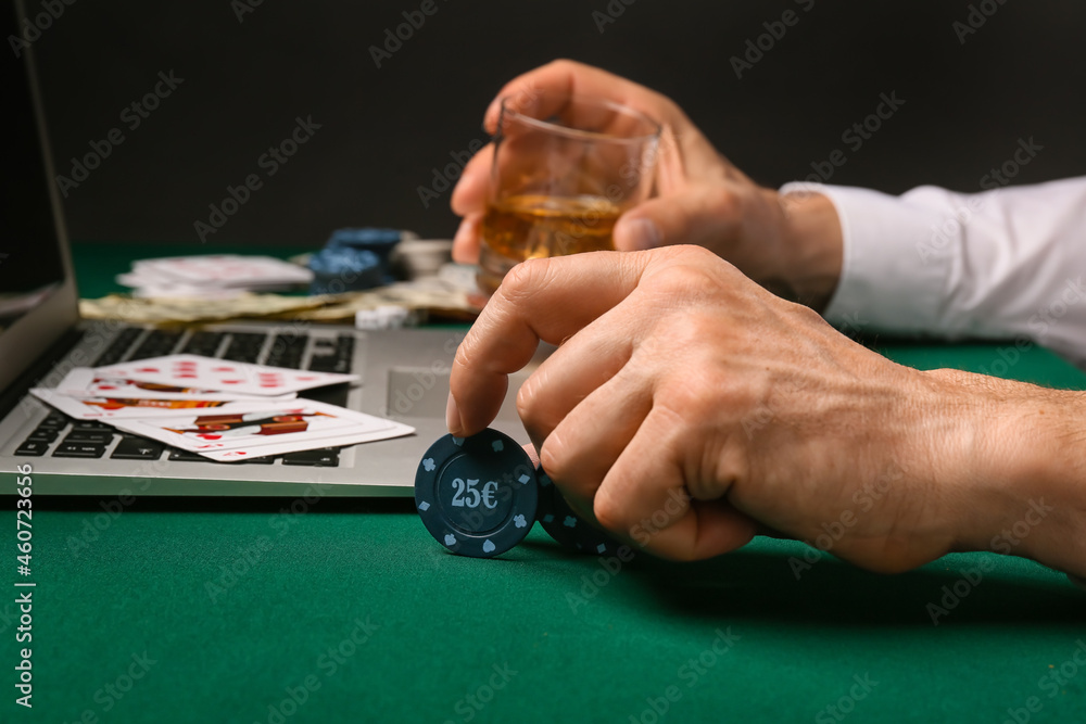 Man with laptop playing poker online at table in casino Man with laptop playing poker online at table in casino