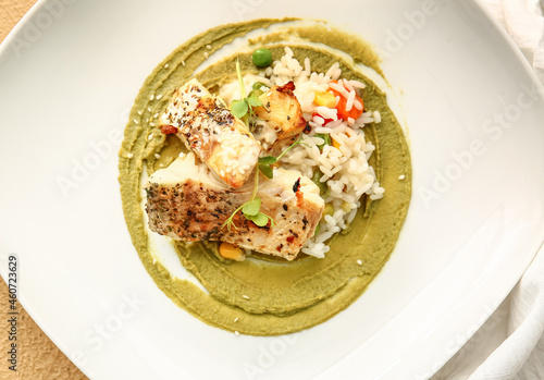 Plate with healthy baked cod fillet, rice and guacamole sauce on color background, closeup