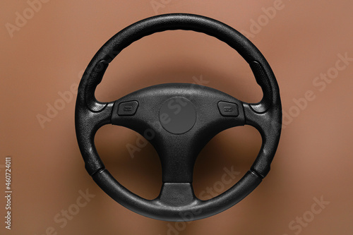 Modern steering wheel on brown background © Pixel-Shot