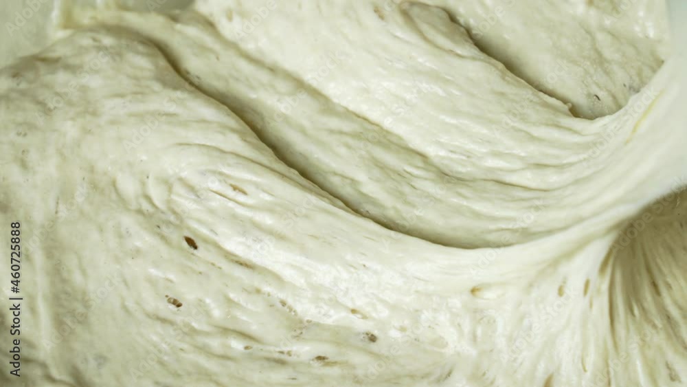 The chef is mixing a yeasty batter with a silicone spatula. Extreme closeup The chef is mixing a yeasty batter with a silicone spatula. Extreme closeup