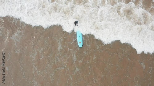Attractive surfer woman carrying her surfboard going out  is crushed by the ocean wave  , fun day at the beach surfing, Sri Lanka.Slowmotion footage