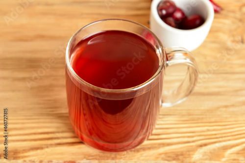 Glass cup of tasty dogwood drink on wooden background, closeup