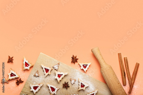 Board with tasty Linzer cookies and rolling pin on color background