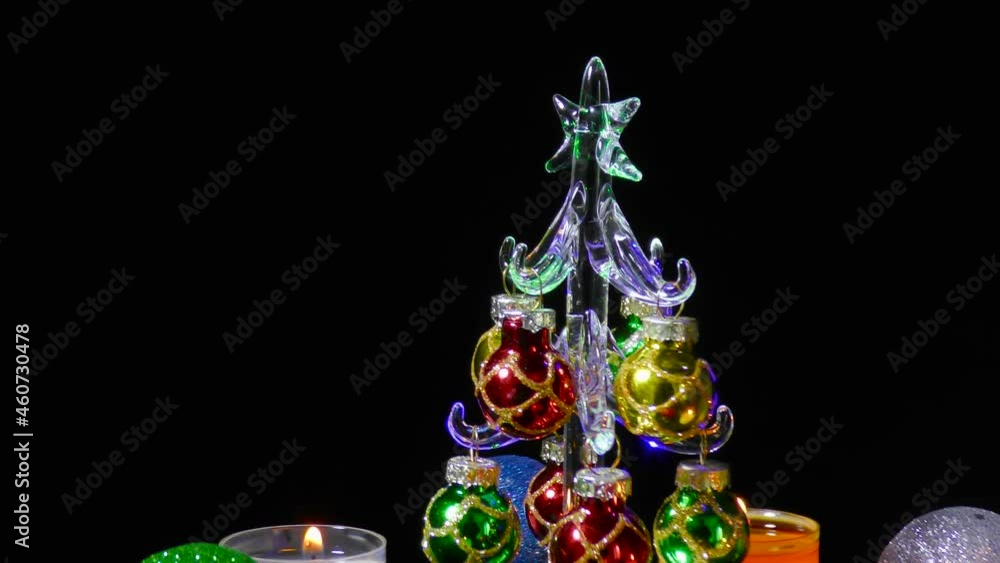 Small Christmas tree revolves surrounded by multi-colored Christmas burning candles and balls Small Christmas tree revolves surrounded by multi-colored Christmas burning candles and balls
