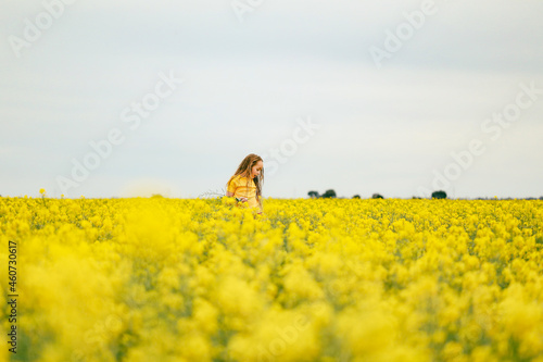 Pretty long haired girl playing in vibrant canola field in full bloom © Caseyjadew