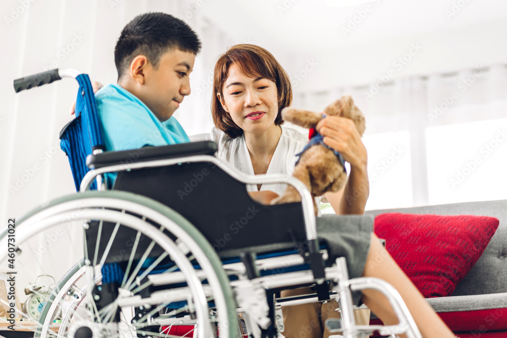 Portrait of enjoy happy love family asian mother playing and carer helping look at disabled son child sitting in wheelchair moments good time at home.disability care concept Portrait of enjoy happy love family asian mother playing and carer helping look at disabled son child sitting in wheelchair moments good time at home.disability care concept