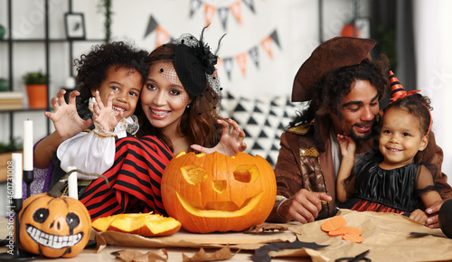 Happy african family parents with kids preparing Halloween decorations at home