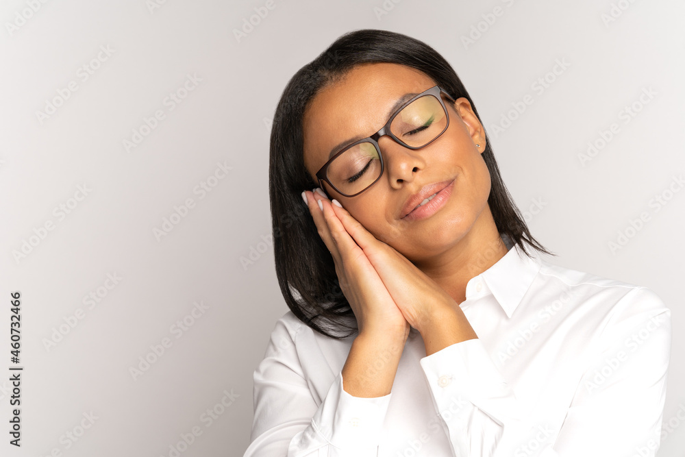 Relaxed african businesswoman lying on folded hands with eyes closed. Exhausted tired at work female in eyeglasses and formal wear need rest and recreation. Calm lady sleeping isolated over gray wall Relaxed african businesswoman lying on folded hands with eyes closed. Exhausted tired at work female in eyeglasses and formal wear need rest and recreation. Calm lady sleeping isolated over gray wall
