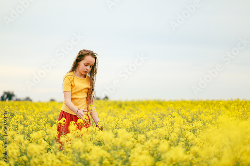 Pretty long haired girl playing in vibrant canola field in full bloom