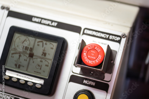 An emergency stop button in red color on the control panel of industrial processing system, it using for stop to process suddenly. Close-up and selective focus.