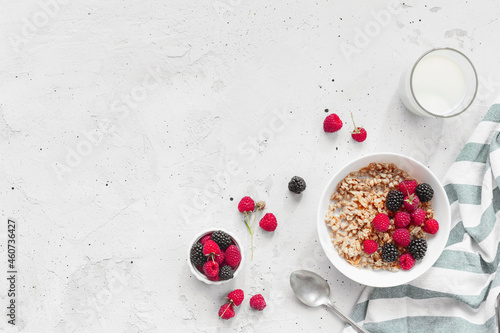 Breakfast bowl with granola, muesli, raspberry, blackberry on gray table