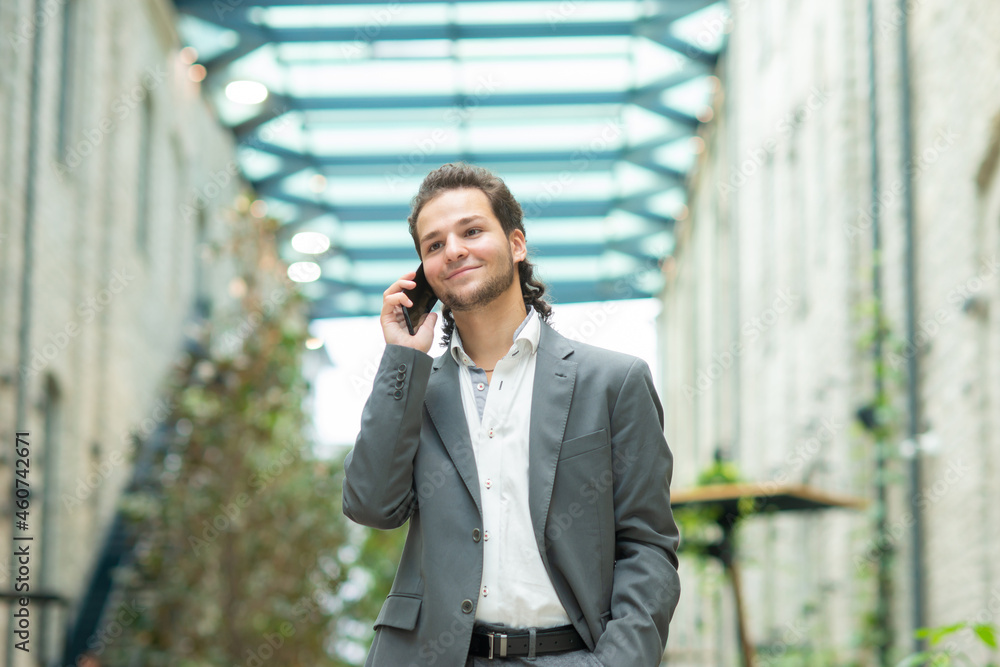 A young successful businessman is working outdoor using smartphone. Man in a casual wear. Business, freelance and remote work. A young successful businessman is working outdoor using smartphone. Man in a casual wear. Business, freelance and remote work.