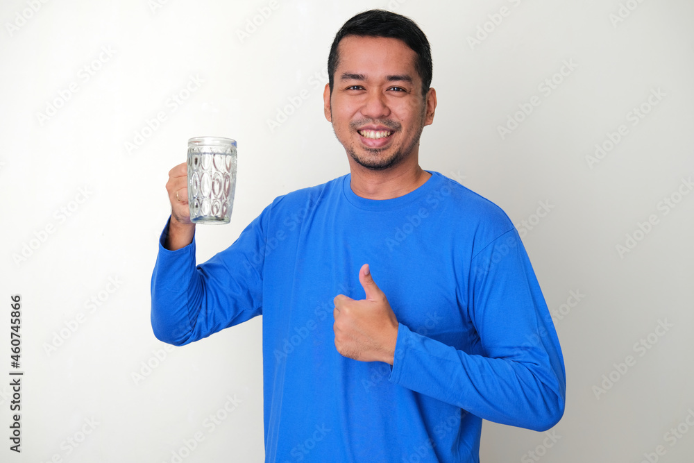 Adult Asian man smiling happy while holding a glass of mineral water Adult Asian man smiling happy while holding a glass of mineral water