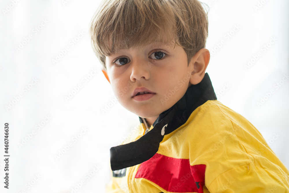 Little Boy Dressed As A Mechanic With A White Background. Child In Car Racing Driver Costume. Image With Copy Space.