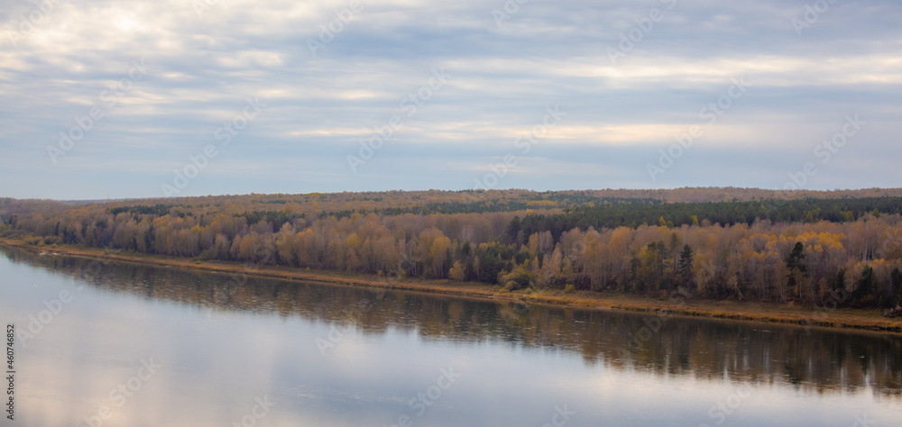 Beautiful, wide river autumn among the woods. Calm and quiet place with autumn colors. In the middle of the river island. View from the top to the distance
