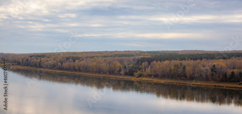 Beautiful, wide river autumn among the woods. Calm and quiet place with autumn colors. In the middle of the river island. View from the top to the distance