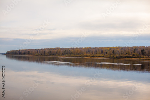 Beautiful  wide river autumn among the woods. Calm and quiet place with autumn colors. In the middle of the river island. View from the top to the distance