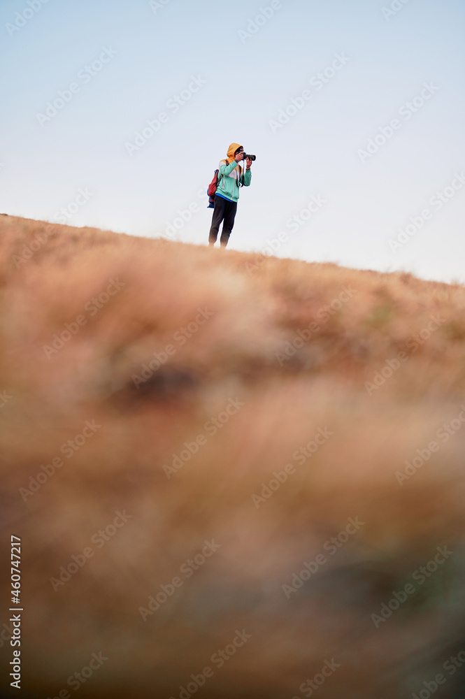 Tourist photographer taking pictures at mountain slope