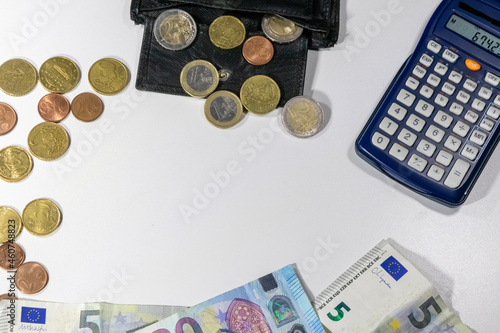 European money with black wallet on white desk as white background with different euro coins and euro bank notes with calculator for financial management and income business plans for tax calculation photo