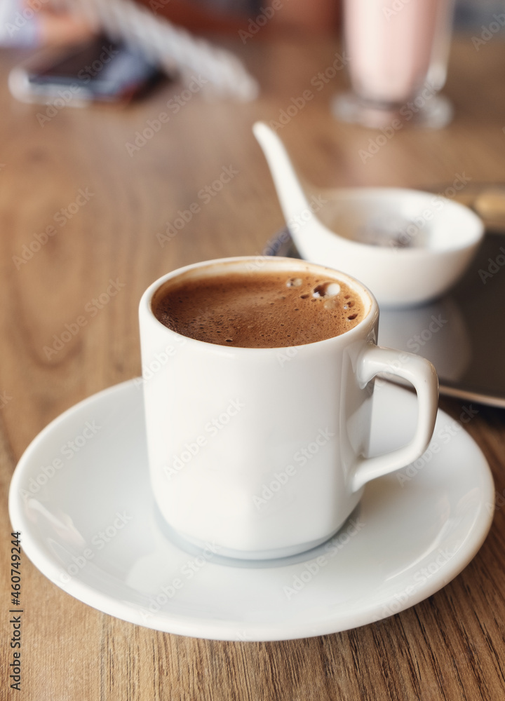 Traditional Turkish coffee in small white cup on wooden table. Selective focus. Vertical photo Traditional Turkish coffee in small white cup on wooden table. Selective focus. Vertical photo
