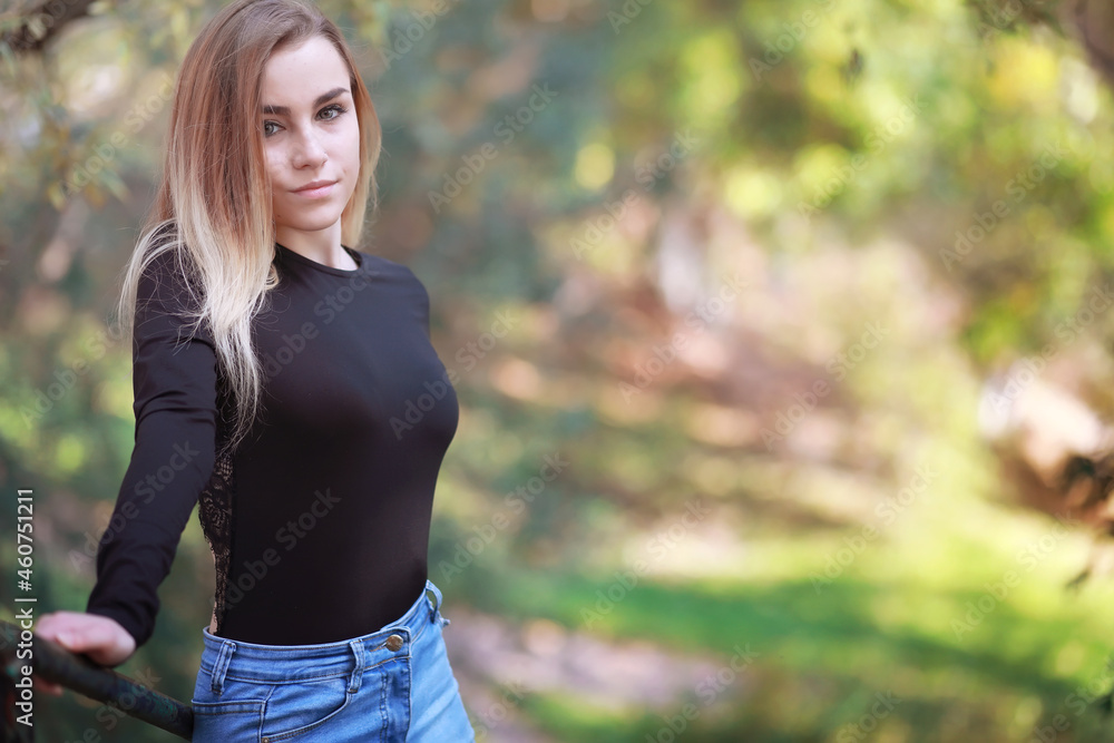 Young beautiful girl on a walk in the autumn park. Leaf fall in the city park. October. Young beautiful girl on a walk in the autumn park. Leaf fall in the city park. October.