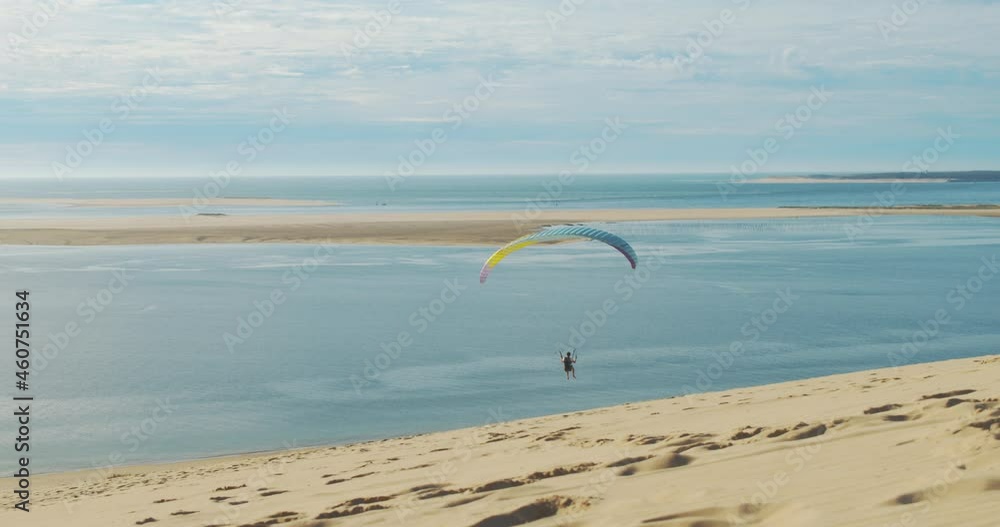 A paraglider coming into land on a gorgeous warm sandy beach with blue waters. A paraglider coming into land on a gorgeous warm sandy beach with blue waters.