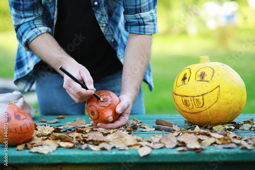Autumn traditions and preparations for the holiday Halloween. A house in nature, a lamp made of pumpkins is cutting out at the table.