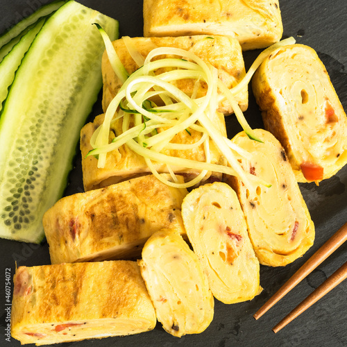 Japanese omelet - tamagoyaki rolls with cucumbers close-up, top view