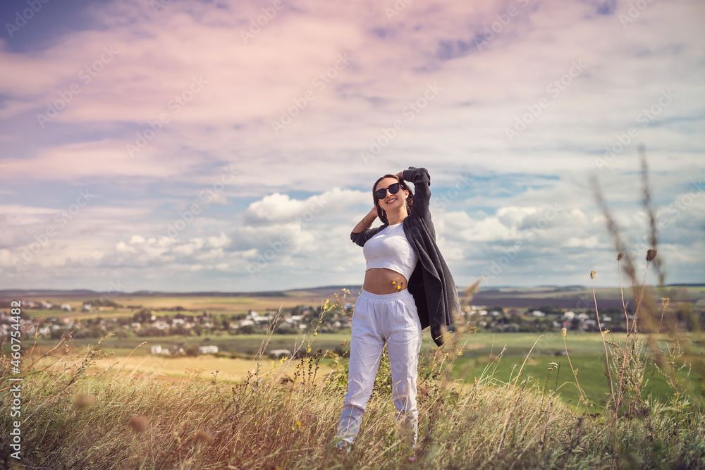 Happy young pretty woman enjoying the landscape near green field Happy young pretty woman enjoying the landscape near green field