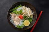 Pho Ga soup  with chicken, rice noodles and fresh herbs in a bowl. Vietnamese cuisine