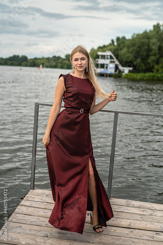 portrait of young woman in a red dress near pond, relax and enjoy summer hot day