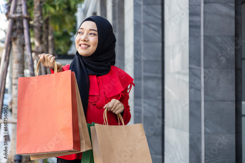 Muslim girl wearing Islamic hijab is in happiness mood after shopping from retail shop in department store