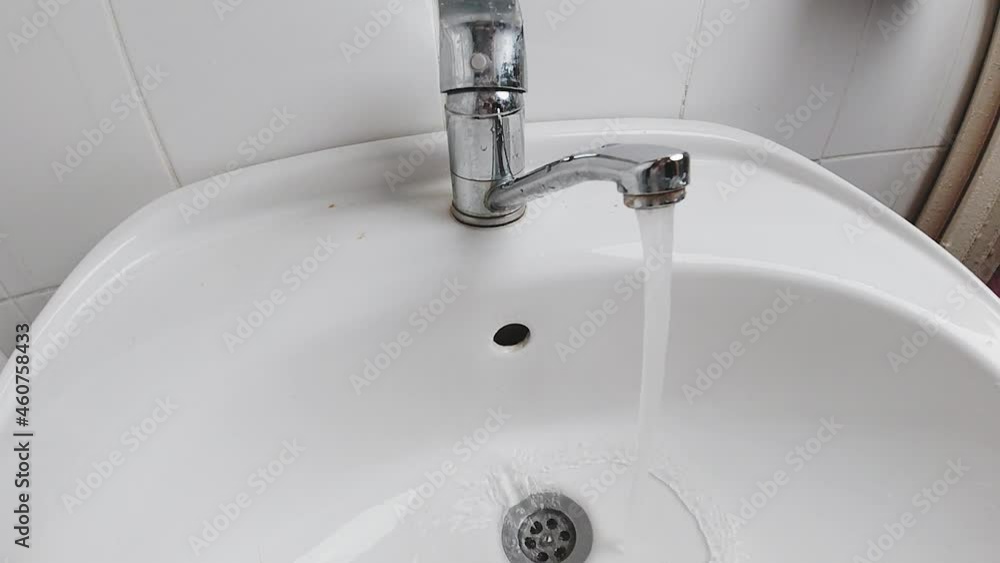 Hand closes the water tap. Close-up shot. Plumber hand closing a water tap at bathroom Hand closes the water tap. Close-up shot. Plumber hand closing a water tap at bathroom