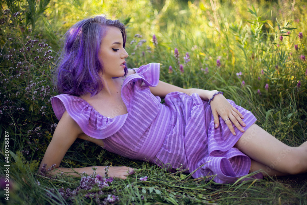 teenage girl with dyed purple hair and a nose piercing in the grass with a bouquet teenage girl with dyed purple hair and a nose piercing in the grass with a bouquet