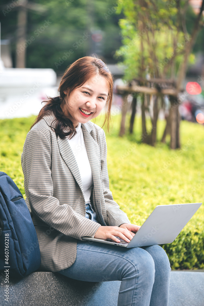 Female college students sit happily working outdoors after school. On campus at sunset with warm light Female college students sit happily working outdoors after school. On campus at sunset with warm light