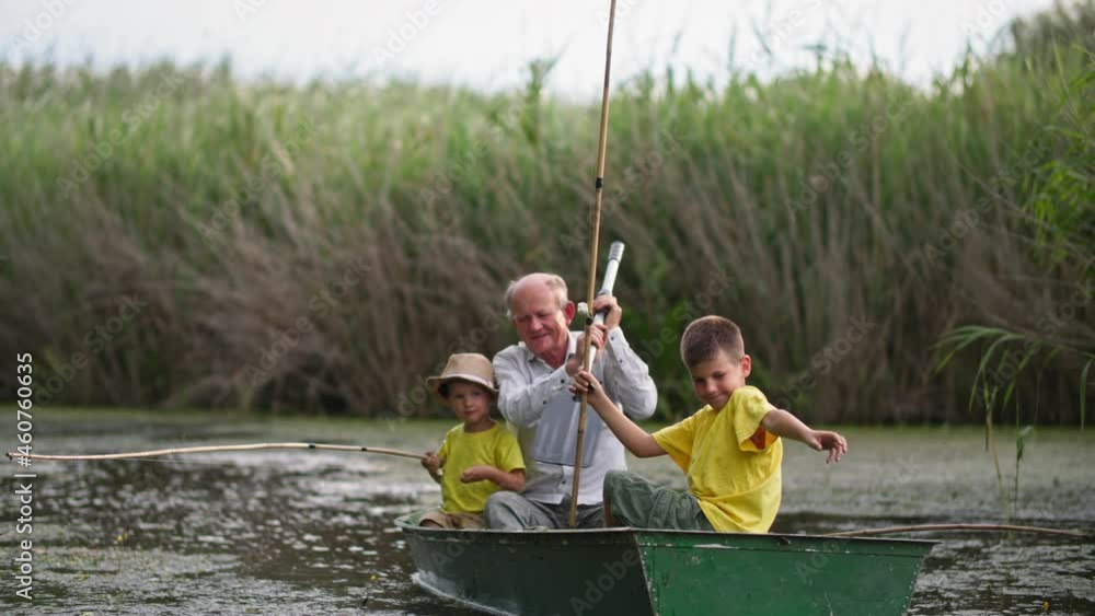 old parent with paddle and children with sticks in boat while fishing, family spends time together on pond on the background of reeds old parent with paddle and children with sticks in boat while fishing, family spends time together on pond on the background of reeds