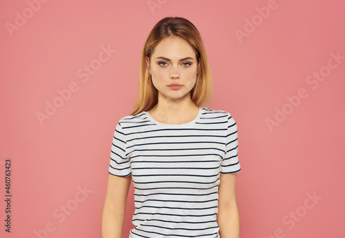 beautiful woman in a striped T-shirt fun hand gestures pink background