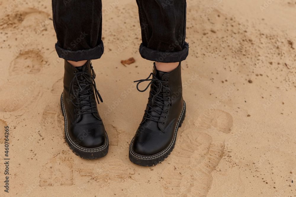 girl's feet in black boots on the sand