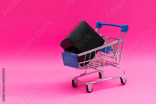 Shopping cart and giftboxes on pink background
