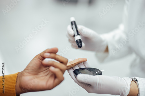 Close-up image of a doctor using blood glucose test kit.