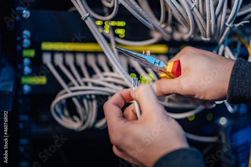 Male hands holding ethernet cable and pliers, close-up. photo