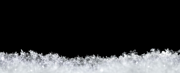 Natural snow texture with snowflakes close-up, isolated on black background with space for text on top. Template for holiday gift cards. Macro texture of snow. Big large size.