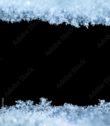 Natural snow texture with snowflakes close-up, isolated on black background with space for text in the center. Template for holiday gift cards. Macro texture of snow.